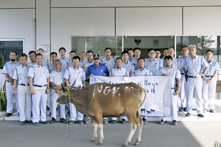 寄付する牛を前に記念撮影。社員が手にしている垂れ幕には企業名が記載されており、犠牲祭会場に掲げられる