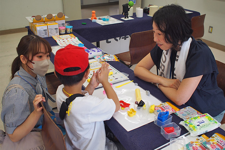 ねんどをこねる子どもを見守る社員