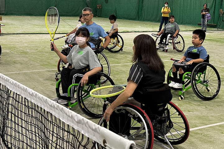 ラケットの持ち方を指導する當間選手（左奥）