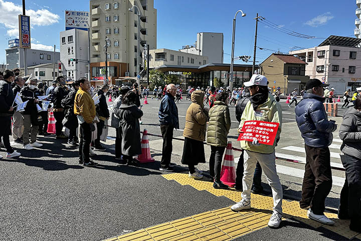 横断歩道を規制しながら、歩行者に迂回（うかい）路を案内する社員